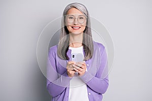 Portrait photo of positive old woman using cellphone texting browsing internet communicating wearing eyeglasses smiling