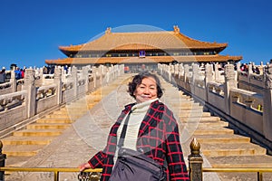 Portrait photo of Senior asian women with `Taihedian ` palace in the Forbidden Palace Gate at beijing