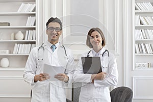Portrait photo of two young smiling doctors in white medical gown in the clinic office