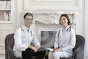 Portrait photo of two young smiling doctors in white medical gown in the clinic office
