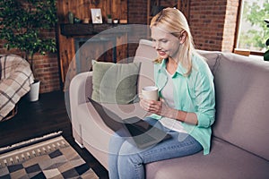 Portrait photo woman smiling using computer sitting on couch drinking coffee browsing internet