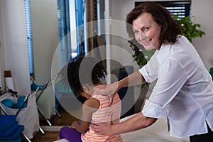 Portrait physiotherapist giving back massage to girl patient