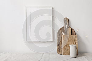 Portrait picture frame mockup. Wooden chopping boards and vase with dry lagurus grass. Beige linen tablecloth. White