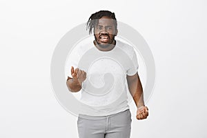 Portrait of off angry fat african-american male model, shaking hand and clenching fists, frowning while shouting