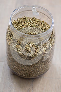 A portrait of a plastic jar or pot full of dried loose fresh viola tricolor leaves to set a fresh cup of tea. The herbs are ready