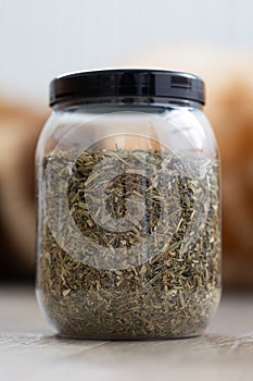 A portrait of a plastic pot or jar full of dried fresh viola tricolor leaves to set a fresh cup of tea. The herbs are ready to be