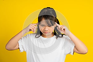 Portrait of playful asian girl sticking fingers in her ears at studio, Child grimacing, playing deaf, making faces