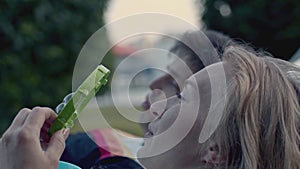 Portrait of playful couple blowing soap bubbles on meadow. Stock. Close up of happy man and woman having fun at romantic