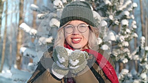Portrait playful young beautiful woman blowing snowflakes at sunlight winter forest closeup slowmo