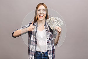 Portrait of a playful young woman with long hair holding bunch of money banknotes and looking at camera, copy space, isolated over