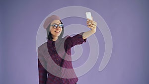 Portrait of playful young woman taking selfie with smartphone camera