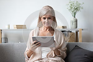 Portrait of pleasant middle aged woman using tablet.