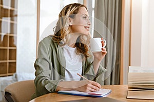 Portrait of pleased blond woman writing down notes