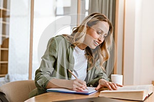Portrait of pleased blond woman writing down notes