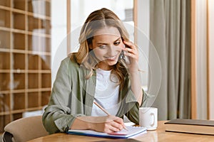 Portrait of pleased blond woman writing down notes