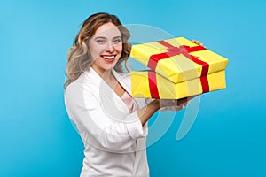 Portrait of pleased charming woman unpacking big present and cute smiling at camera. blue background