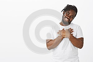 Portrait of pleased cute plump african-american guy with beard and moustache, tilting head and smiling from heartwarming