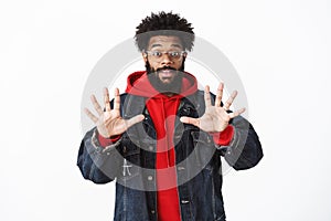 Portrait of pleased and friendly-looking african-american bearded male in glasses raising hands showing number ten or photo