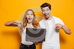 Portrait of pleased positive man and woman holding and pointing