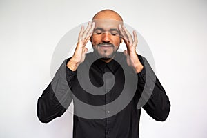 Portrait of pleased young man rubbing temples