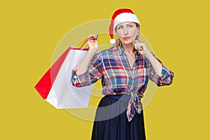 Portrait of pondering modern middle aged woman in red santa cap