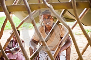 Portrait of a poor, elderly Indian woman behind a fence in the form of a lattice