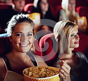 Portrait, popcorn and a woman in the cinema watching a movie for entertainment while eating a snack. Face, smile and