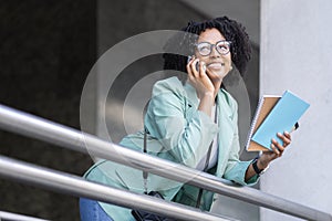Portrait of positive african woman have phone conversation at office