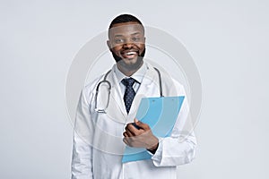 Portrait of positive black doctor holding medical chart