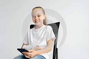 Portrait of positive blonde little girl with broken arm wrapped in white plaster bandage smiling looking at camera