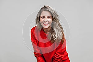 Portrait of positive blonde woman with red lipstick in bright casual sweater, isolated on gray background