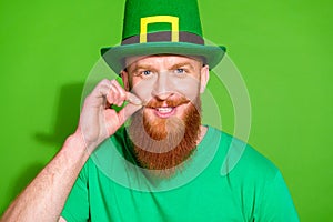 Portrait of positive charismatic man arm fingers make mustache curls isolated on green color background