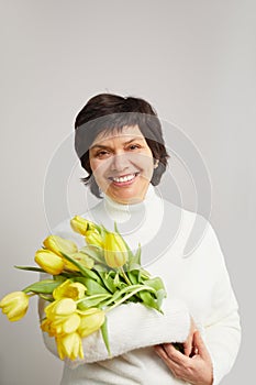 Portrait of positive charming cheerful old woman granny receive bunch of tulips smell close eyes enjoy 8-march celebration.