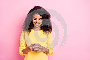 Portrait of positive cheerful black lady feel interested use her cell phone read feednews in social network account wear