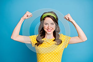 Portrait of positive cheerful girl show her hand muscles wear polka-dot clothes isolated over blue color background
