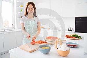 Portrait of positive cheerful housewife woman enjoy cooking junk unhealthy food cut tomato chopping board yummy pizza