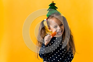 Portrait positive cheerful smiling happy little schoolgirl girl Christmas tree decoration polka dot dress biting eat