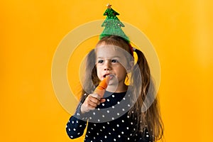 Portrait positive cheerful smiling happy little schoolgirl girl Christmas tree decoration polka dot dress biting eat