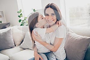 Portrait of positive cheerful sweet mommy and her little girl kiss mommy cuddle embrace enjoy spend free time together