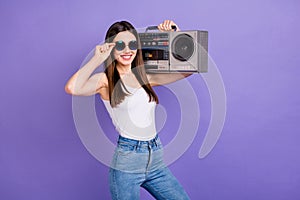 Portrait of positive cheerful youth girl enjoy listen retro music hold shoulders boom box wear sunglass good look outfit