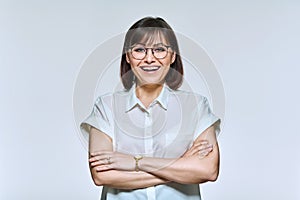 Portrait of positive confident middle aged woman looking at camera, on light background