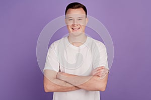 Portrait of positive cool guy crossed arms shiny white smile on violet background