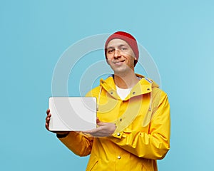 Portrait of positive cool man showing blank white screen of tablet, male isolated on blue color