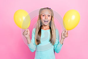 Portrait of positive excited girl toothy smile arms hold yellow balloons isolated on pink color background