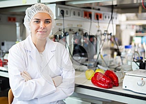 Portrait of a positive female laboratory assistant in uniform in biochemical laboratory