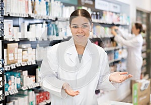 Portrait of positive female pharmacist who invites you to visit a pharmacy or healing cosmetics store