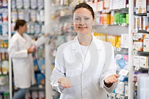 Portrait of positive female pharmacist who invites you to visit a pharmacy or healing cosmetics store