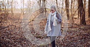 Portrait of positive female walking in woods in autumn