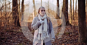 Portrait of positive female walking in woods in autumn