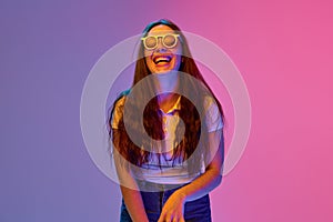 Portrait of positive and funny young brunette woman in sunglasses smiling and laughing against gradient background in